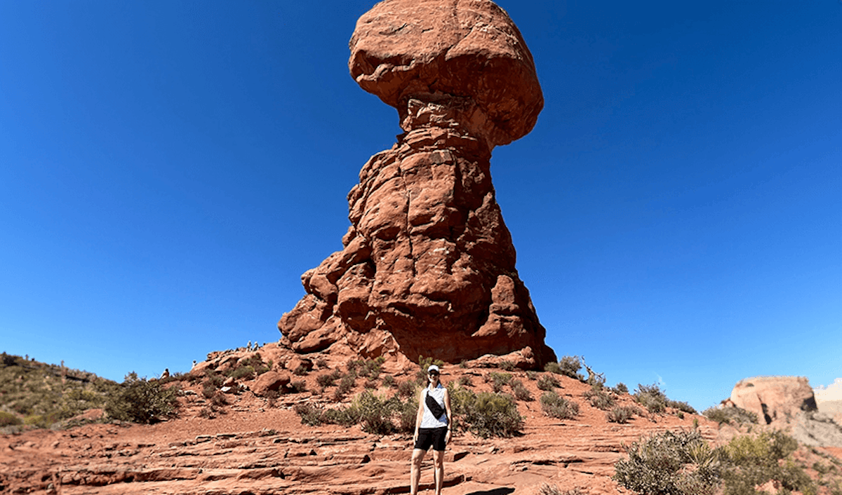 A person standing in front of a large rock formation.