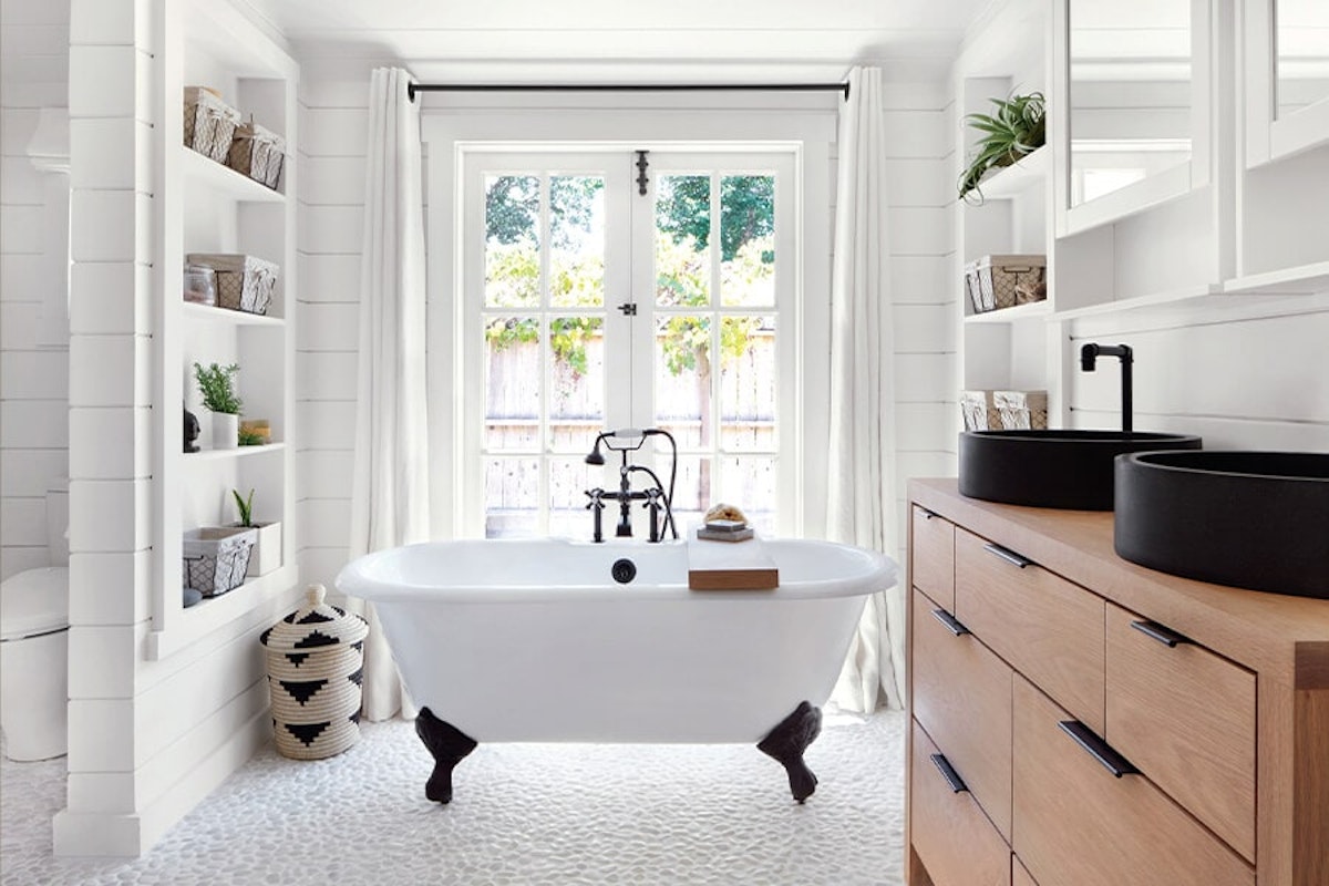 A white bathroom with a tub and shelves.