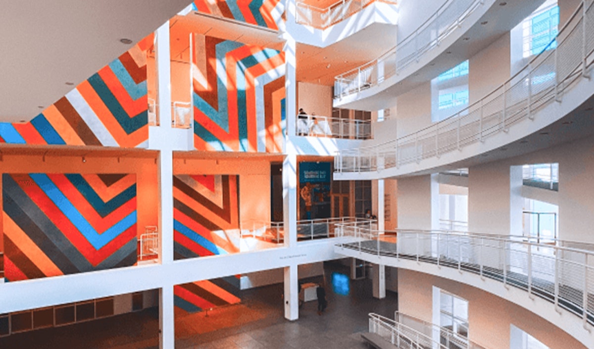Modern gallery interior with vibrant orange and blue striped wall art.