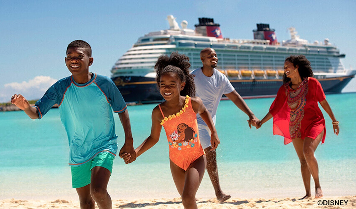 A family walking on the beach with a disney cruise ship in the background.