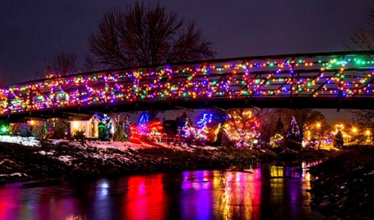 A bridge with christmas lights over a river.