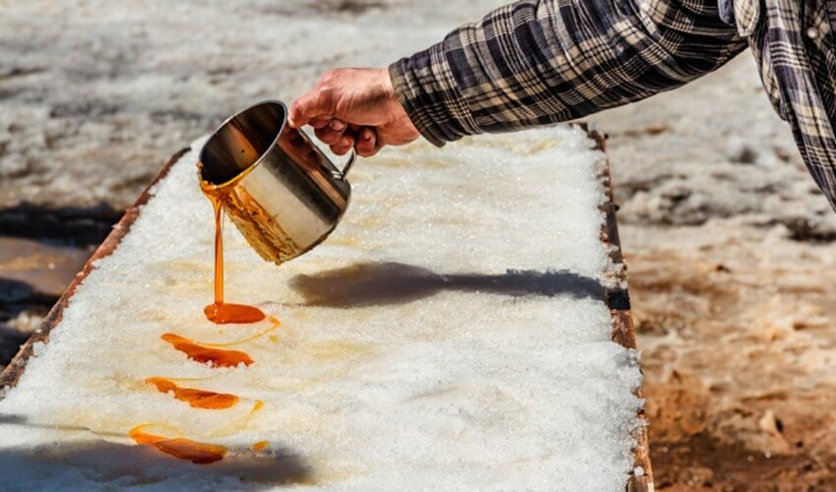 A man pouring a liquid onto a piece of snow.