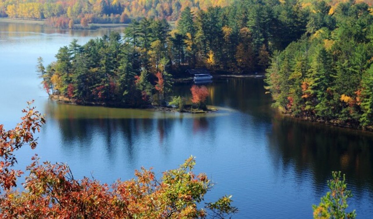 A lake surrounded by trees and fall foliage.