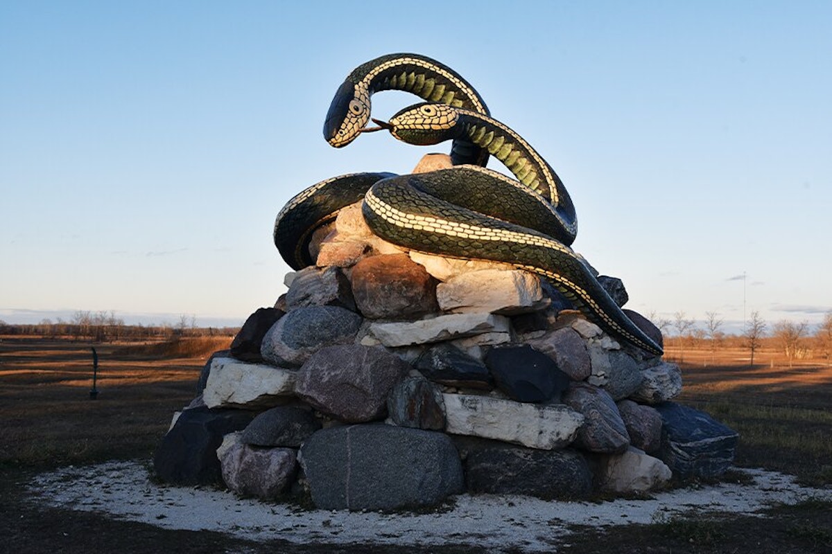 A statue of a snake on top of a pile of rocks.