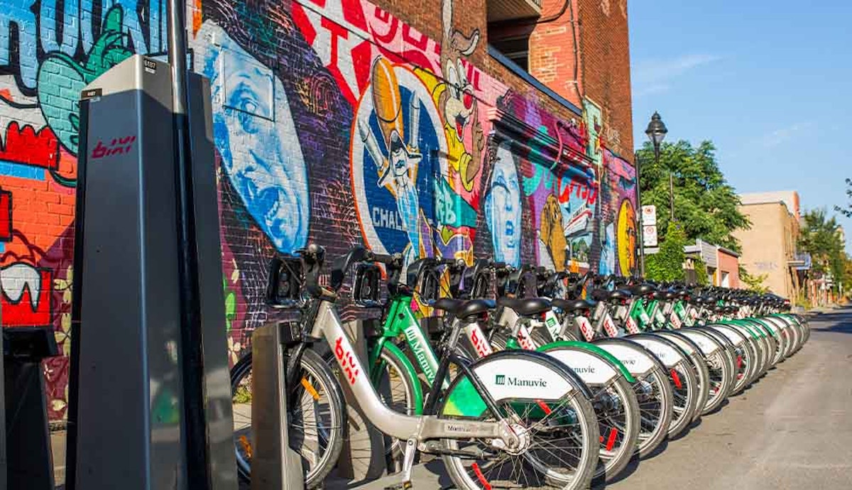 A row of bicycles parked in front of a brick wall.