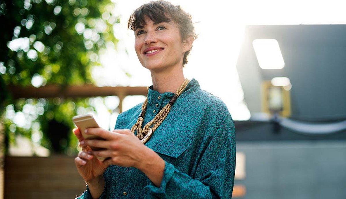 A woman holding a cell phone and smiling.