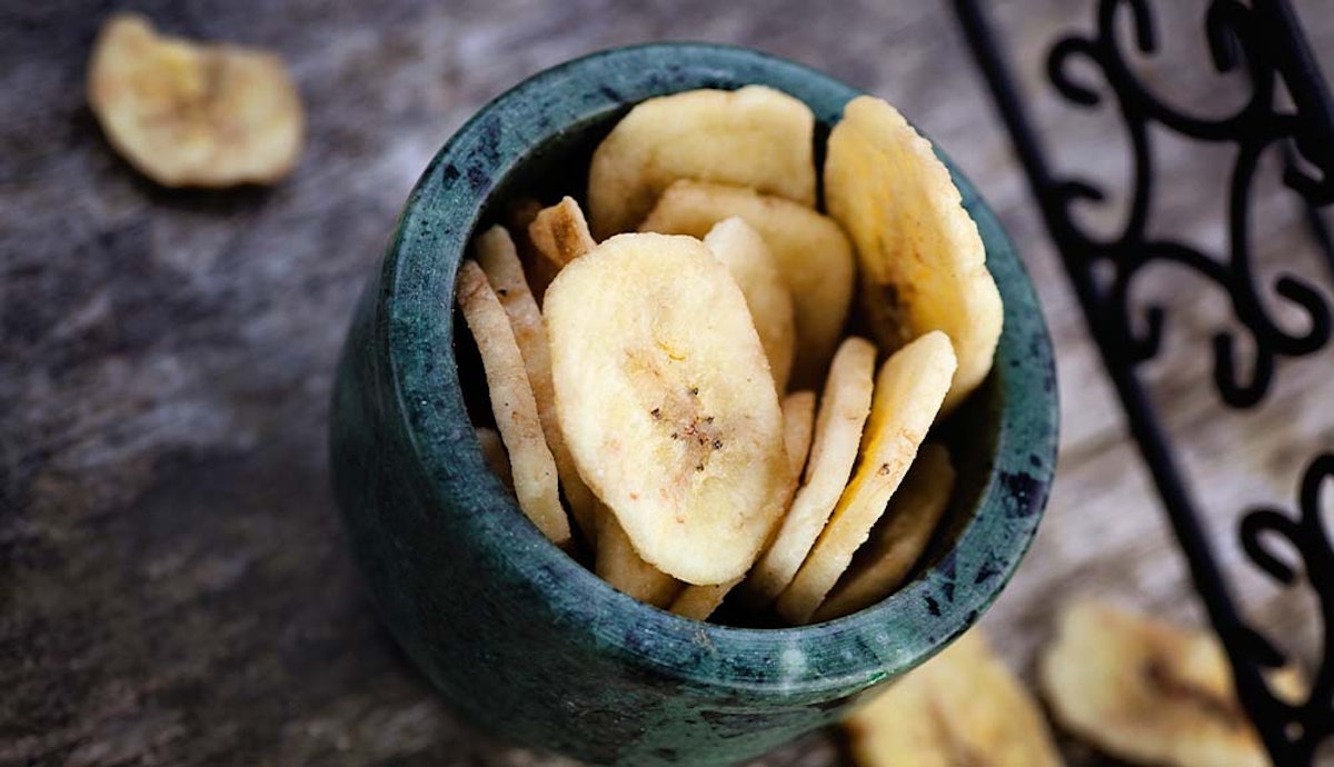 Banana chips in a bowl on a wooden table.