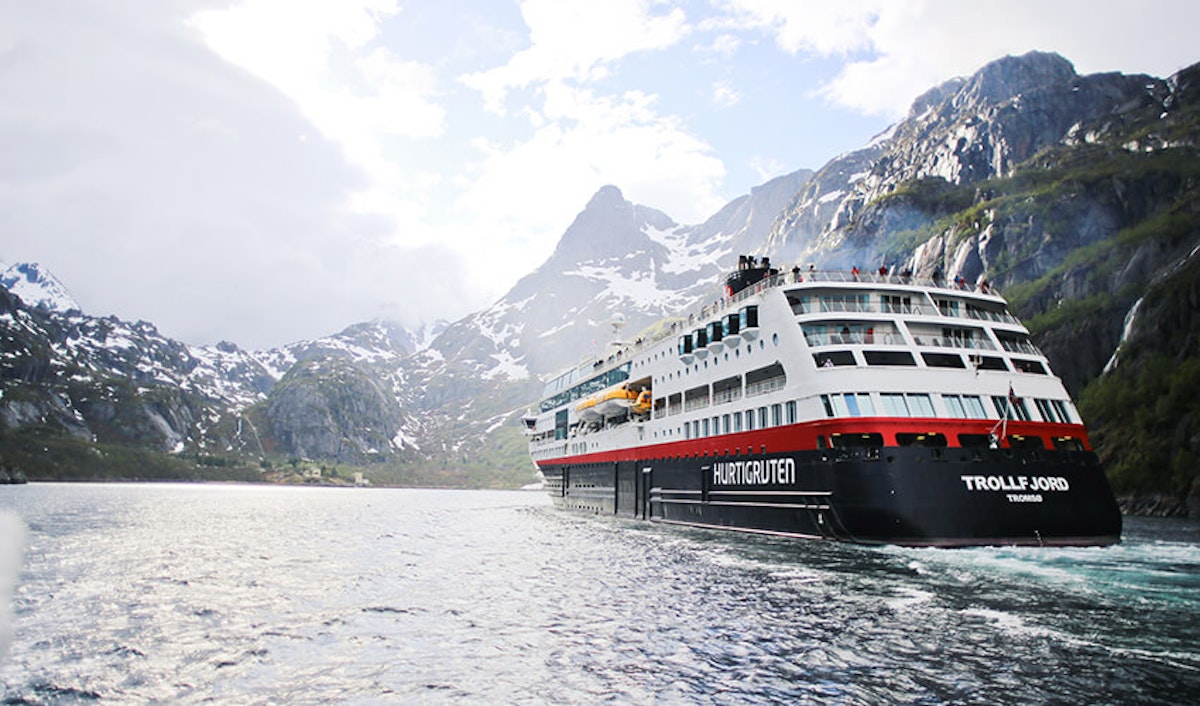 A large cruise ship in the middle of a body of water with mountains in the background.