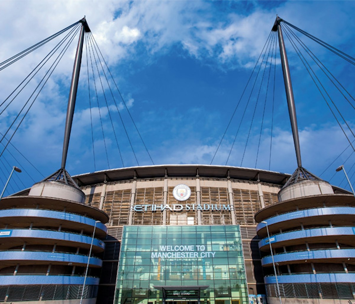 The etihad stadium under a blue sky with clouds, home to manchester city football club.