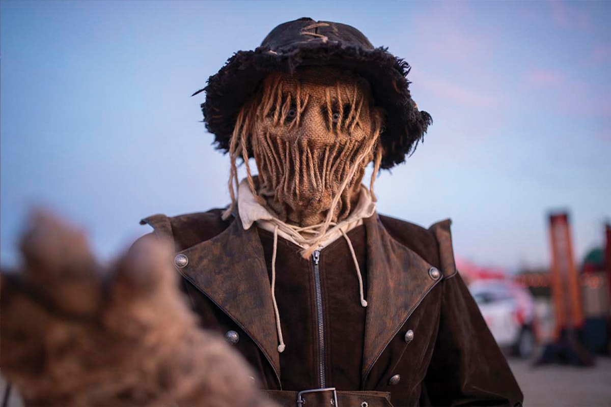 Person wearing a scarecrow costume with a burlap mask and straw hair.