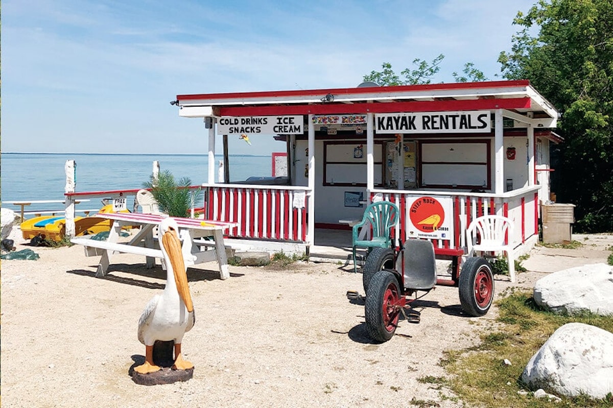 A small ice cream shop with a pelican statue on the side of the road.
