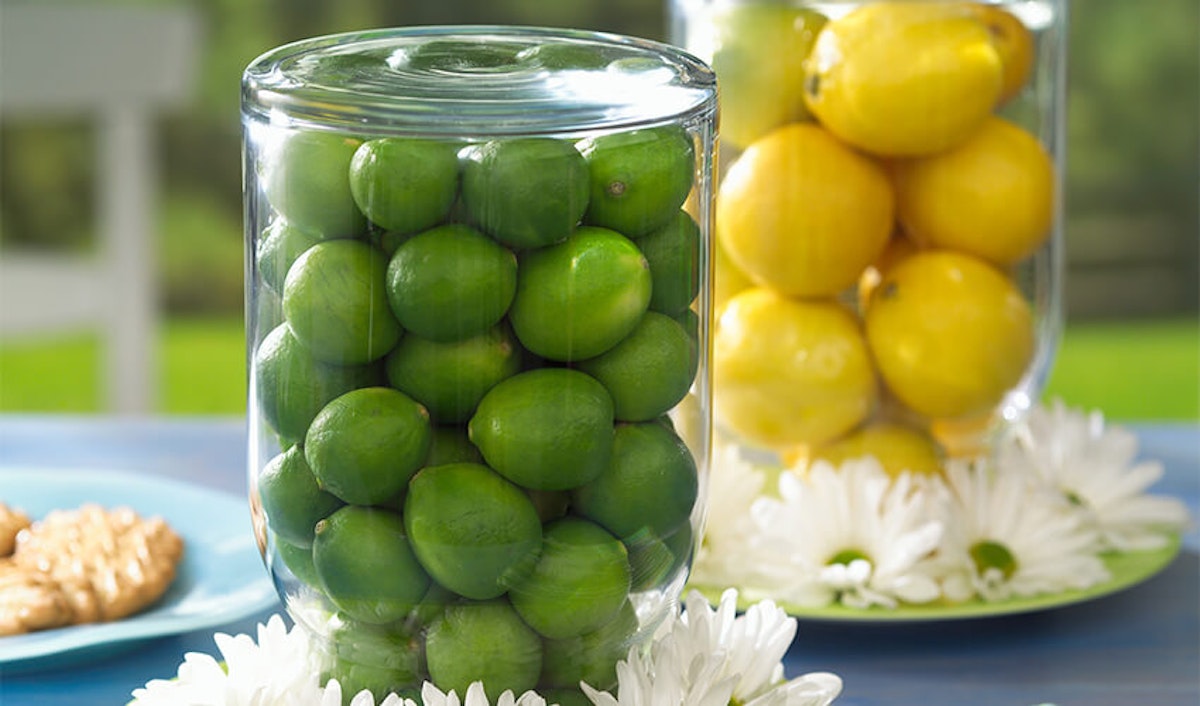 Two jars of lemons and limes on a table.