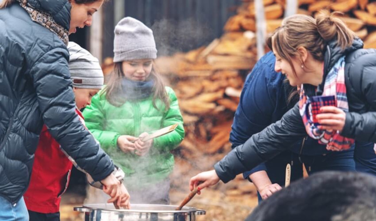 A group of people preparing food in front of a fire.