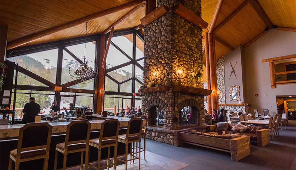 The lobby of a lodge with a large stone fireplace.
