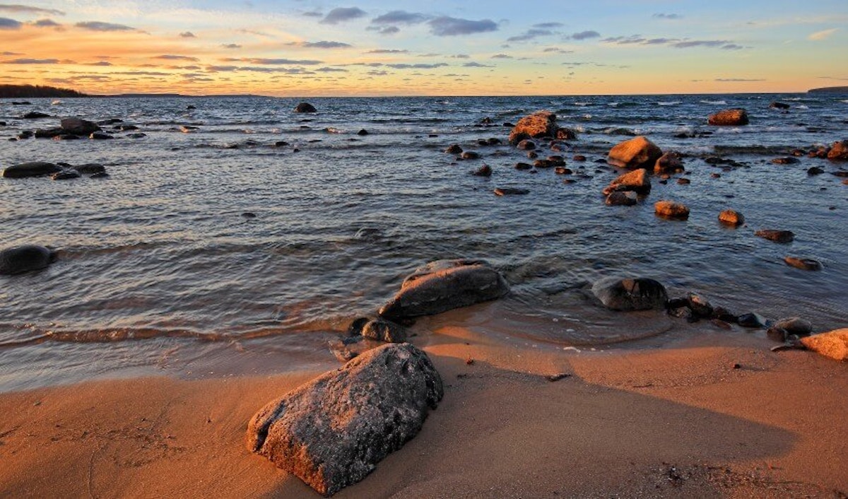 A beach with rocks and water at sunset.