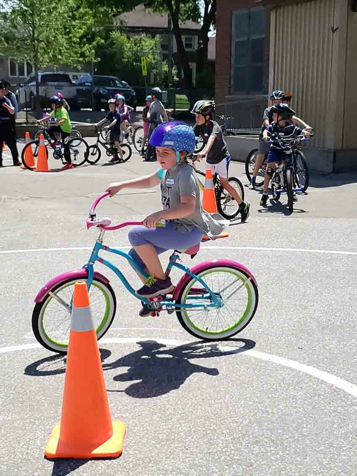 A young girl riding a bike in a group of cones.