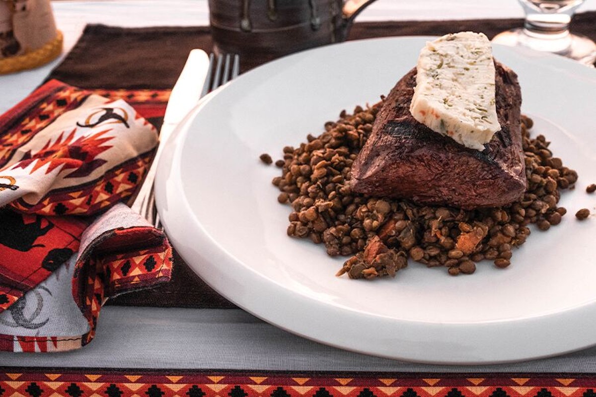 A plate with a steak and lentils on it.