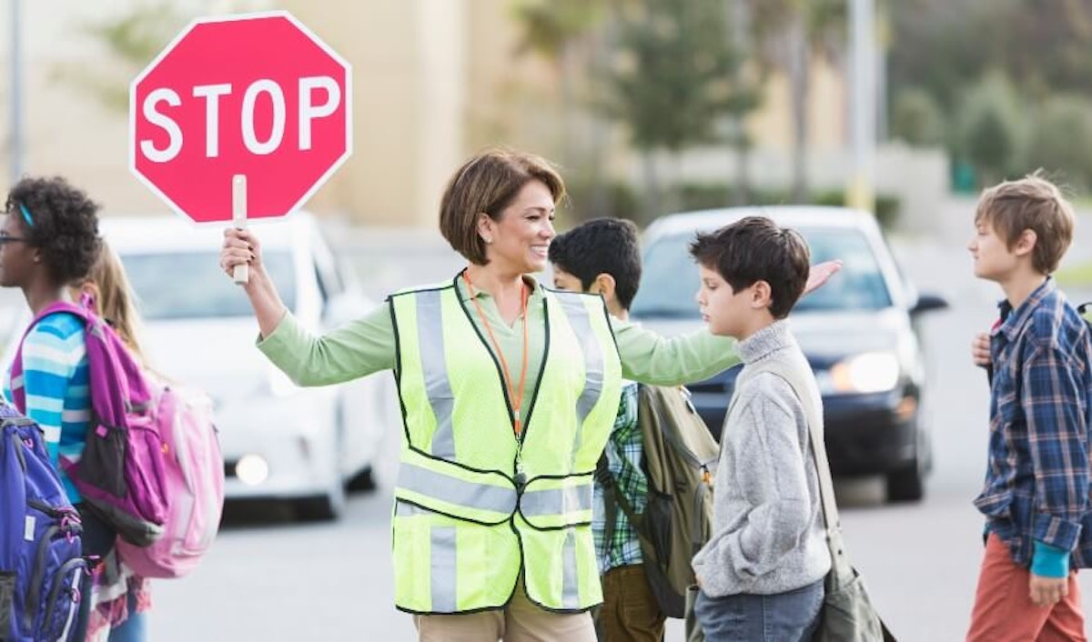 A woman holding a stop sign in front of a group of children.