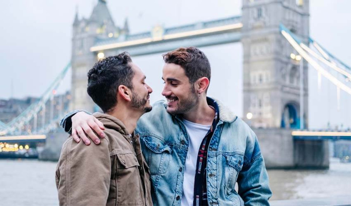 Two men hugging in front of tower bridge in london.