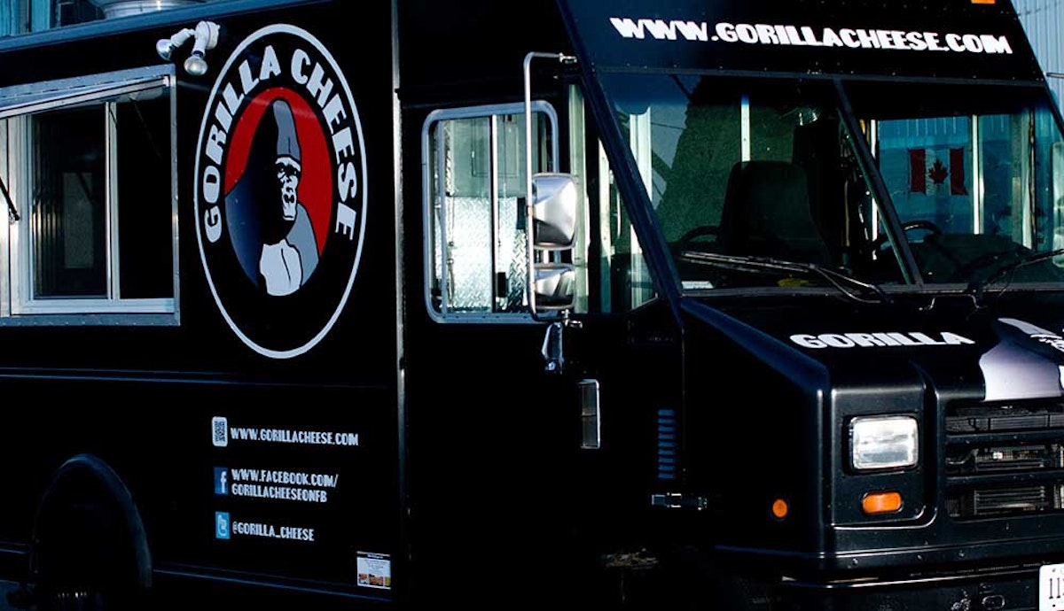 A black food truck parked in front of a building.