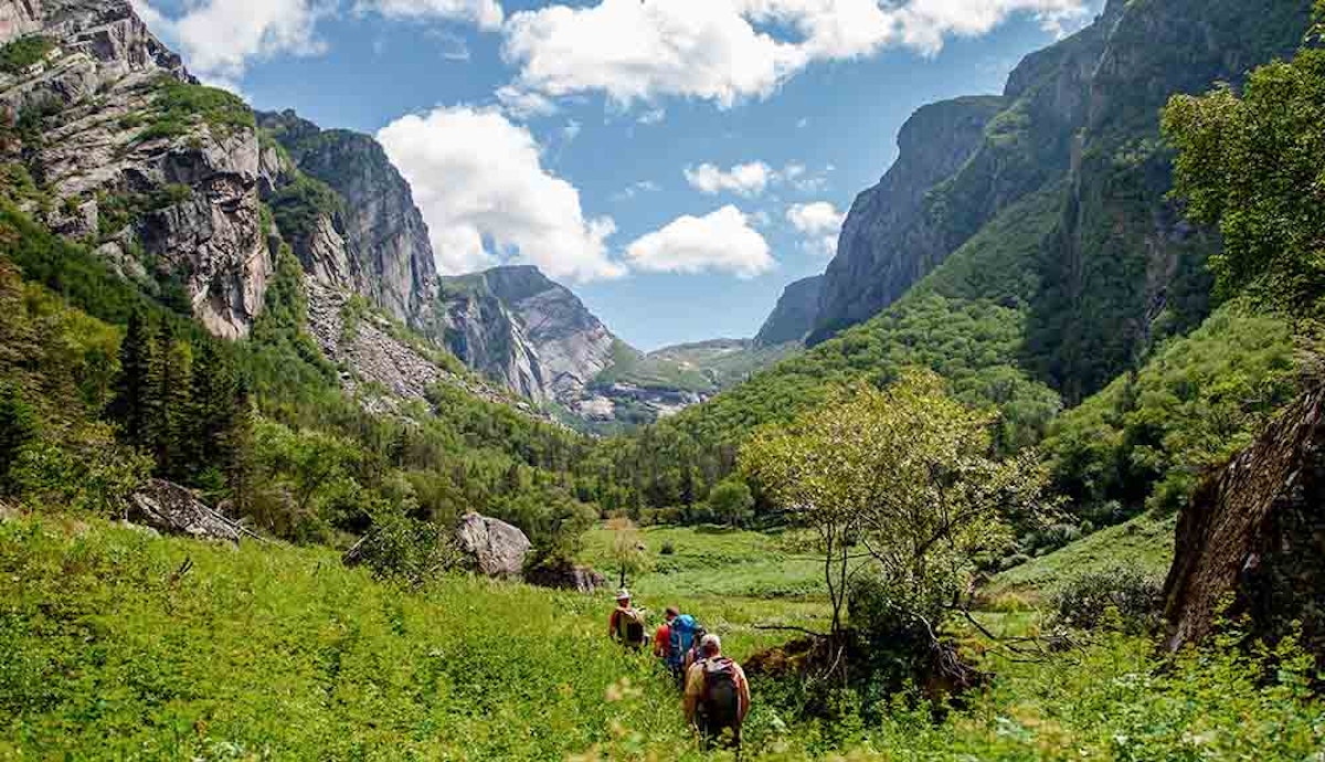 A group of people riding horses through a canyon.