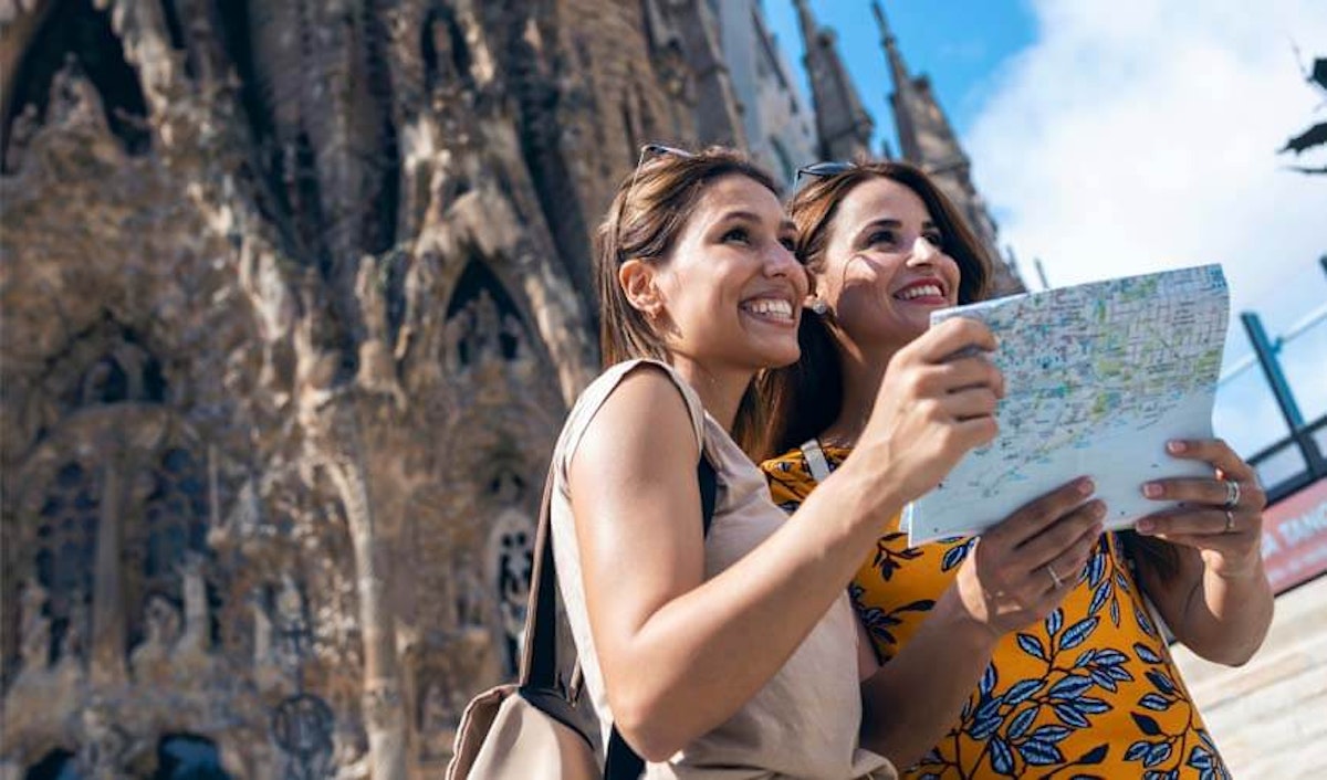 Two women looking at a map in front of a cathedral.
