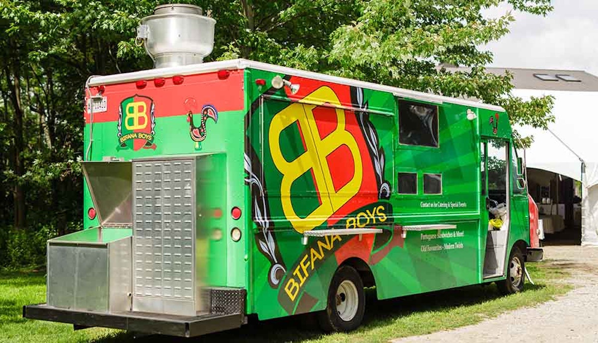 A green and red food truck parked in front of a tent.