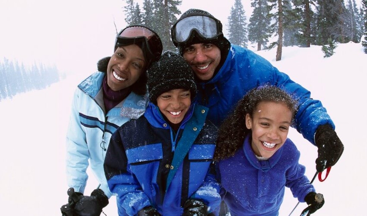 A family smiling while skiing in the snow.
