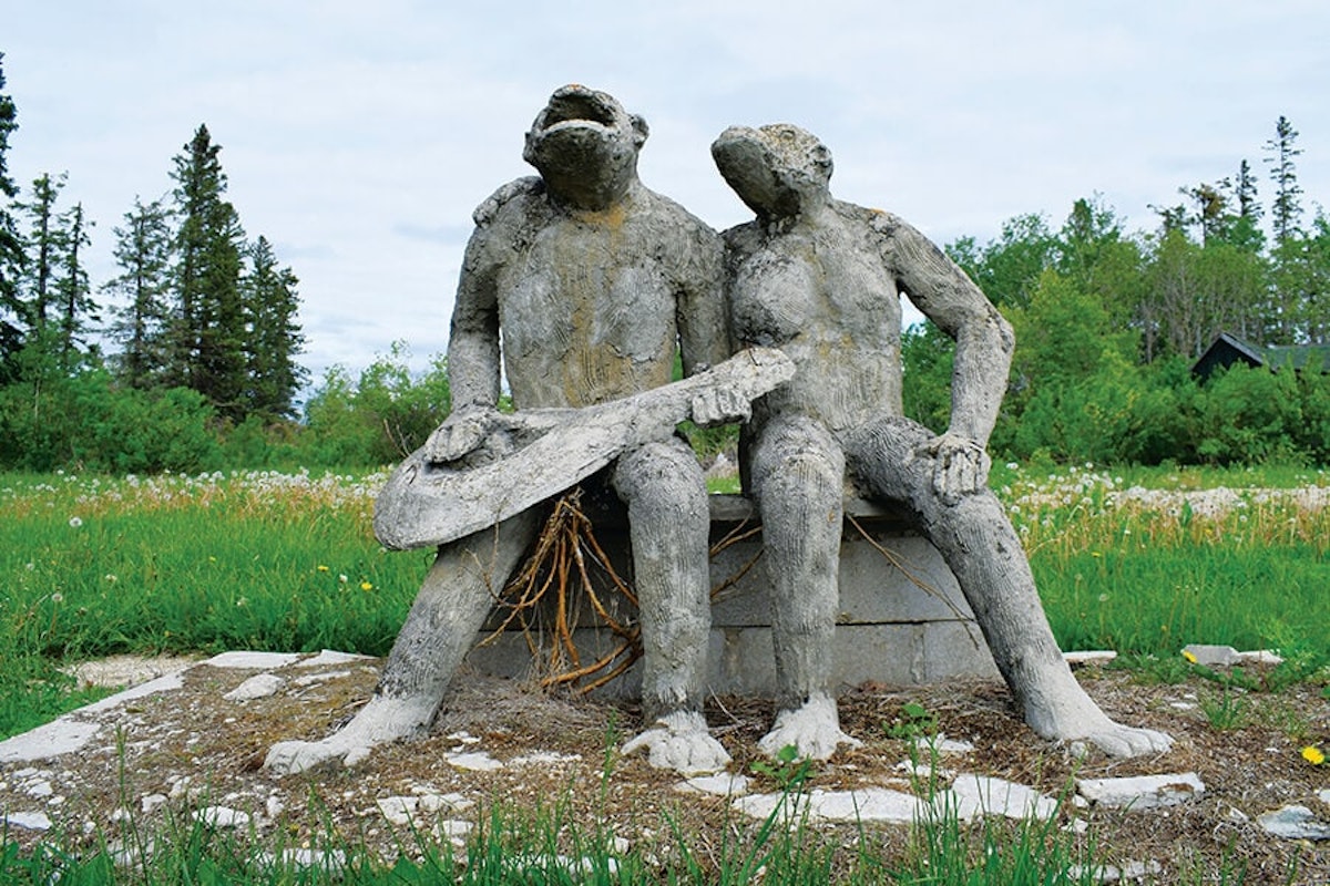 A statue of two people sitting on a stone bench.
