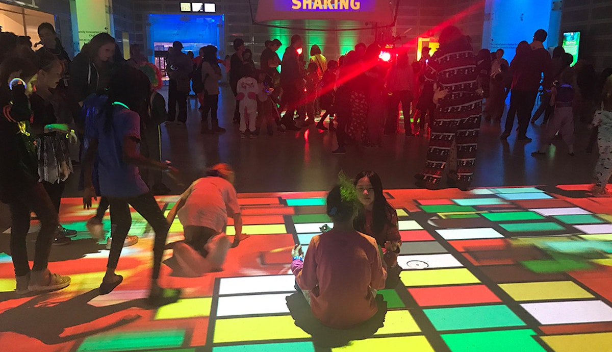 A group of people playing on a colorful dance floor.