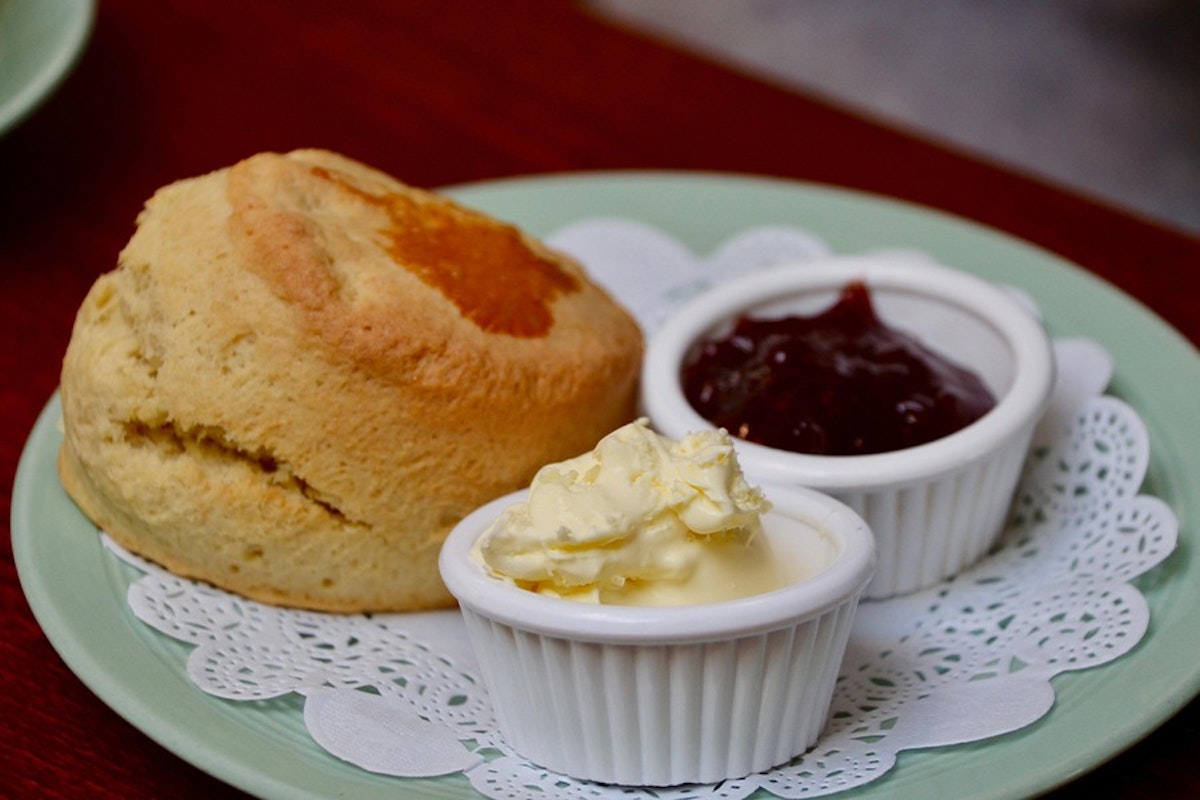 A scone served with clotted cream and jam on a plate.