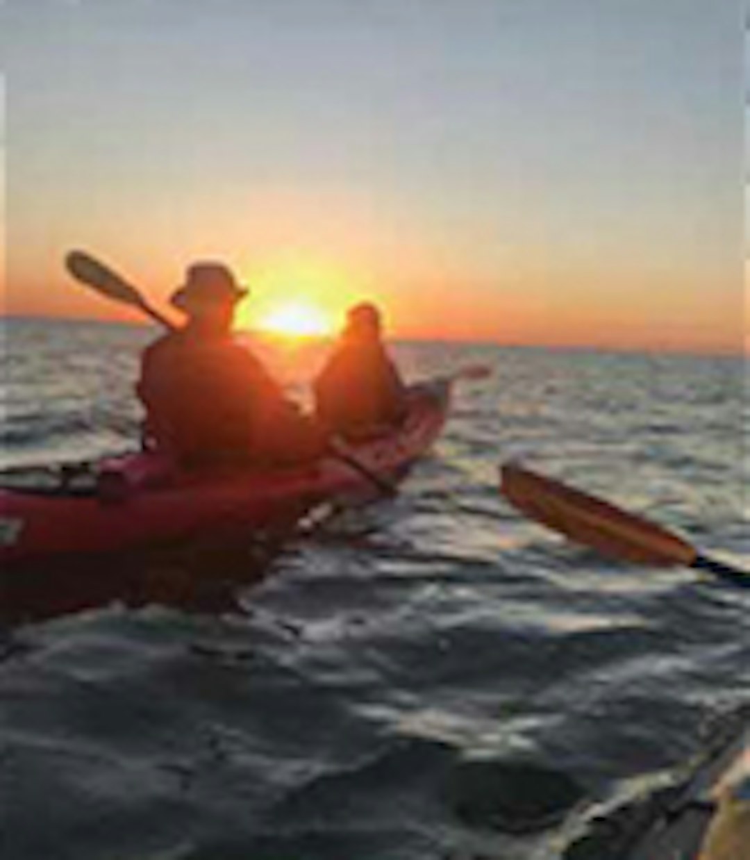 Two individuals kayaking at sunset.