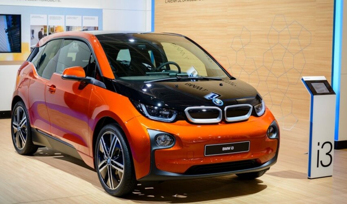 An orange bmw i3 is on display in a showroom.