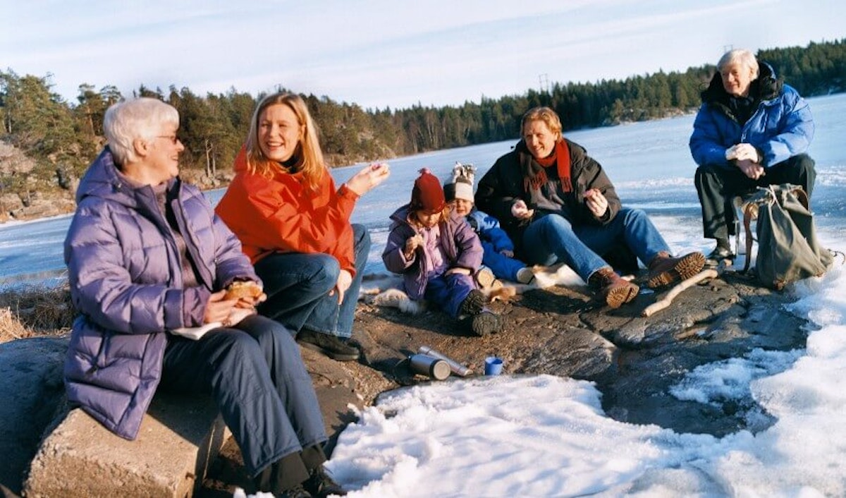 A group of people sitting on rocks near a body of water.