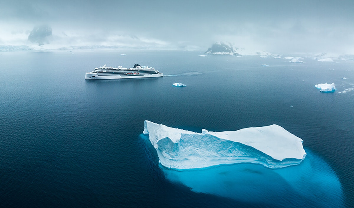 A cruise ship is in the water near an iceberg.