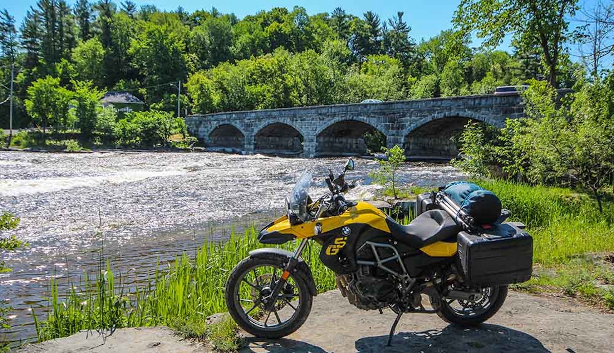 A motorcycle parked on a rock near a river.