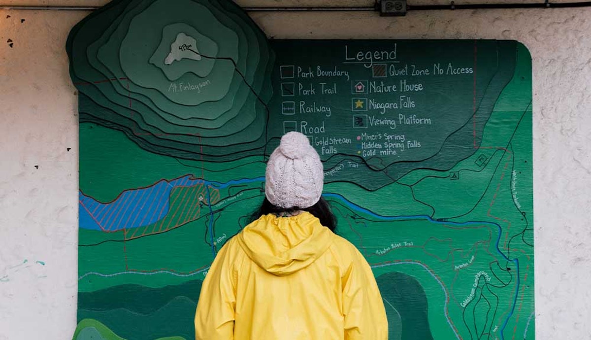A woman in a yellow raincoat looking at a map.