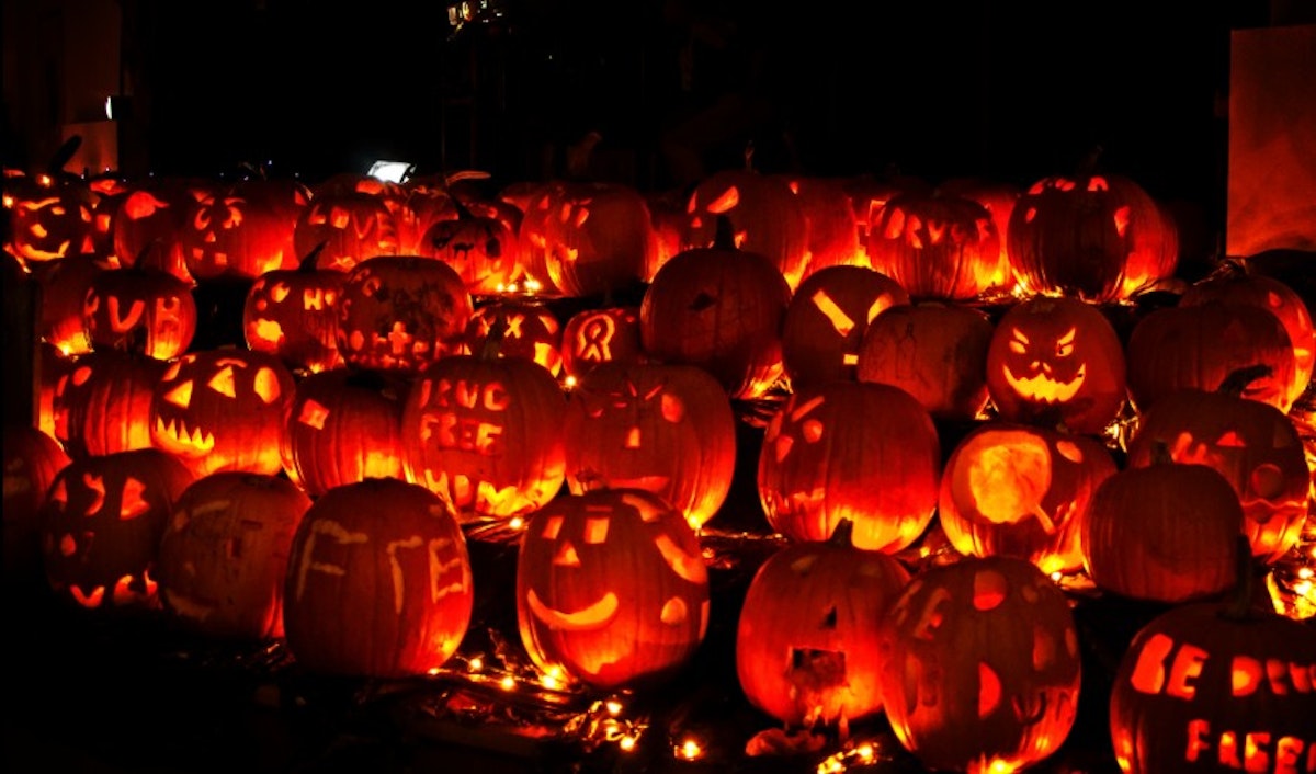 Many carved pumpkins are lit up at night.