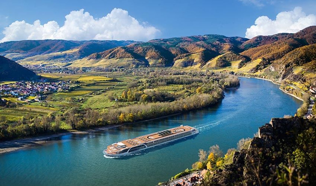 A cruise ship traveling down a river in a valley.