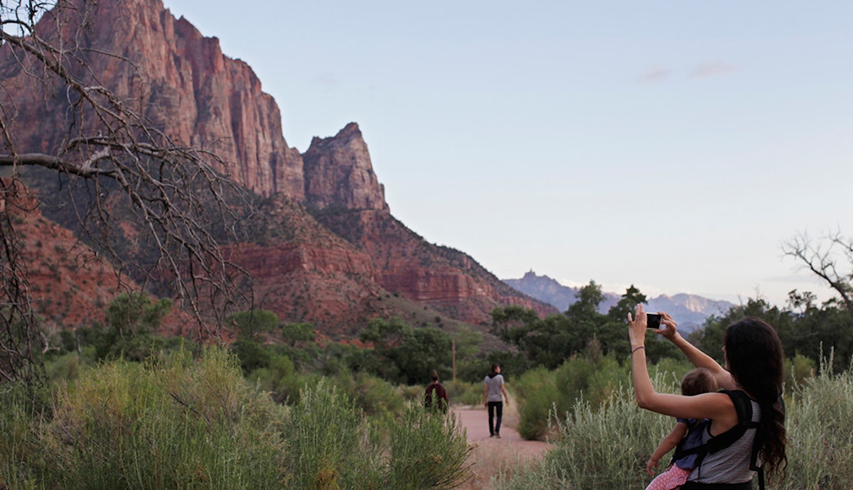 A woman is taking a picture of a mountain.