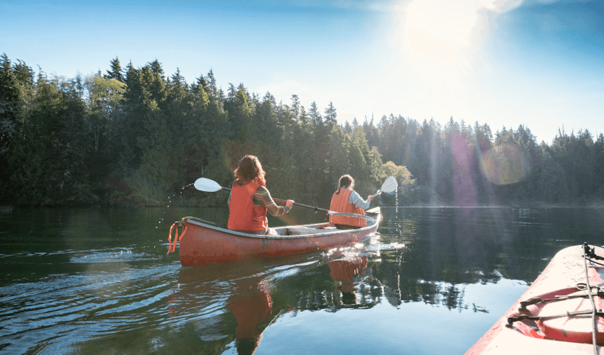 Two people paddling in a canoe on a lake.