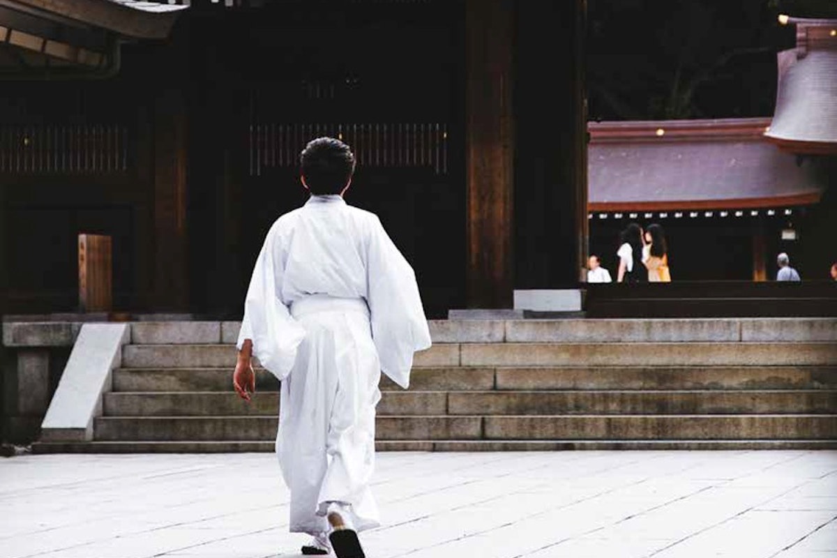 A woman in a white kimono walking down steps.