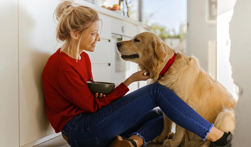 A woman is sitting on the floor with her dog.