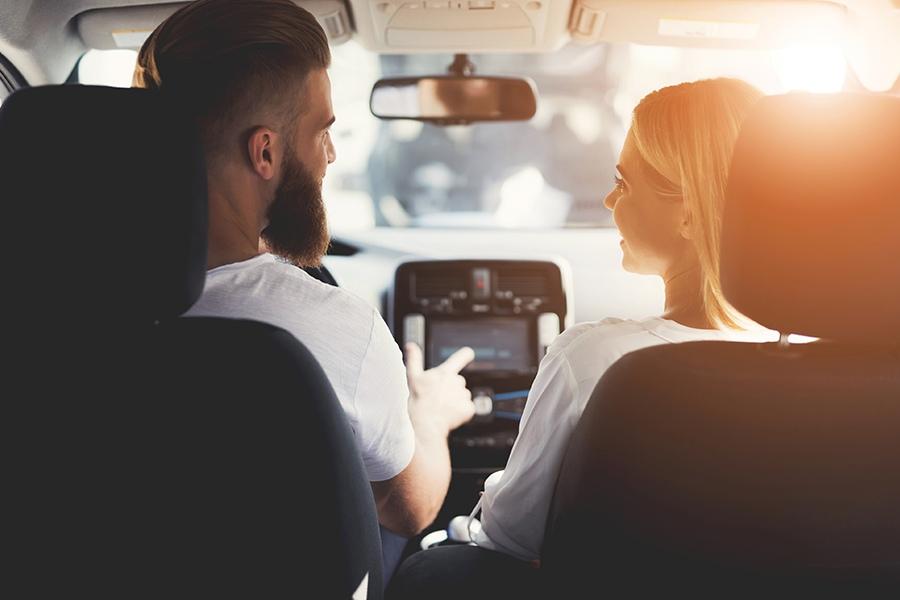A man and woman are sitting in the back seat of a car.
