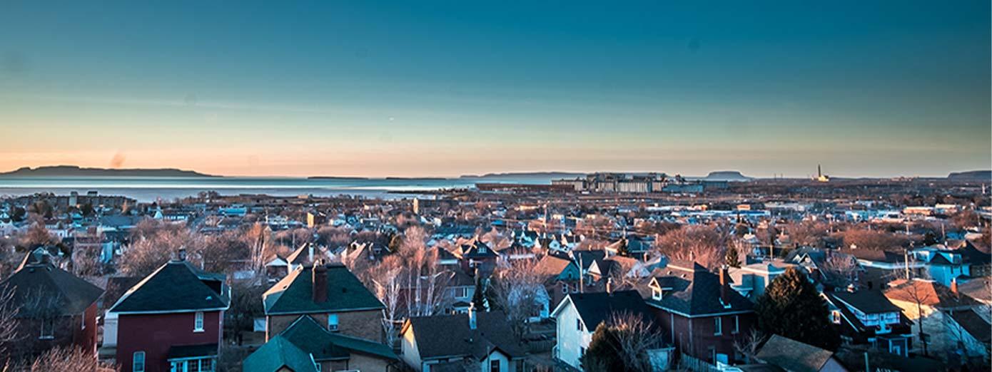 An aerial view of Thunder Bay, ON, featuring the iconic Sleeping Giant rock formation in the distance across Lake Superior.