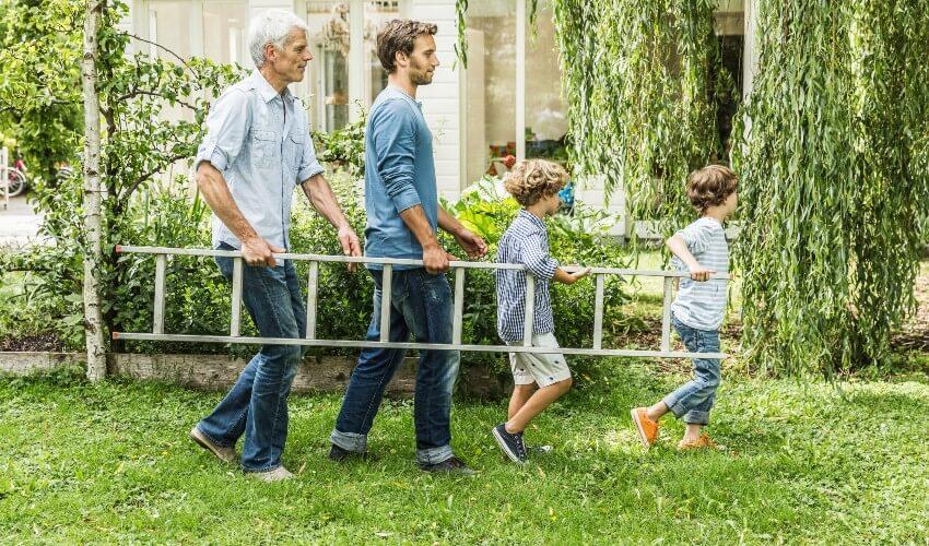 A group of people walking with a ladder in the yard.