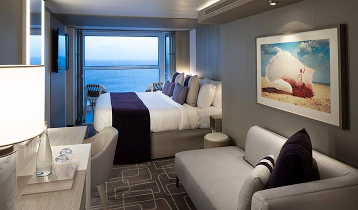 A bedroom on a cruise ship with a view of the ocean.
