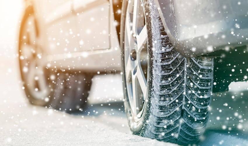 A close up of a car tire on a snowy road.