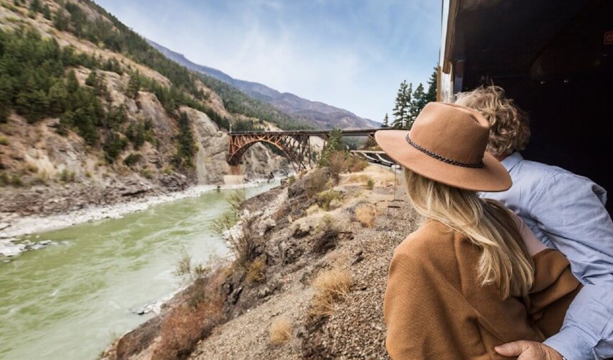 A couple on a train looking out over a river.