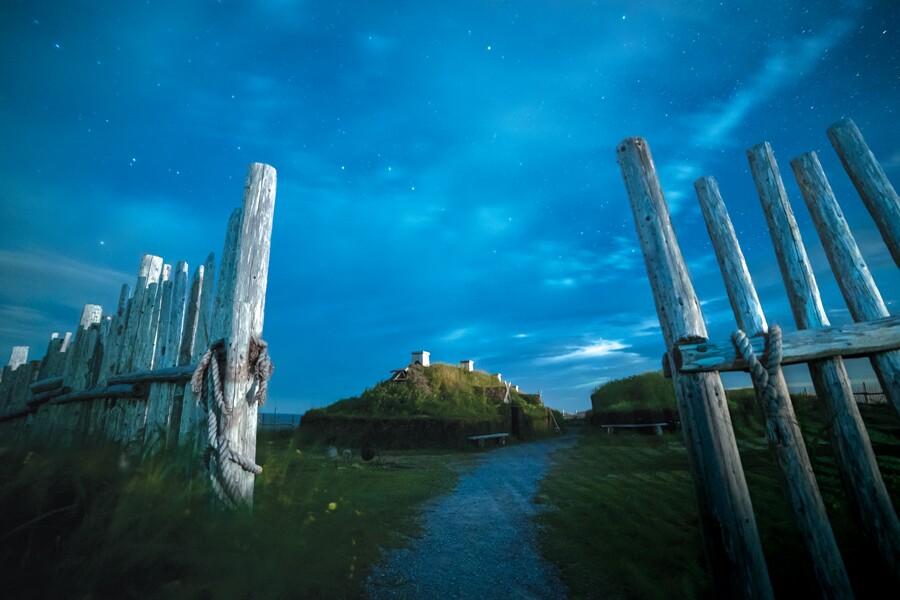A wooden fence with a starry sky behind it.